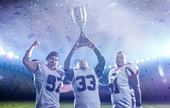 happy american football team with trophy celebrating victory in the cup final on big modern stadium with lights and flares at night