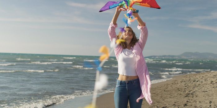 Loving Couple Flying A Kite at Beach and having fun on autumn day