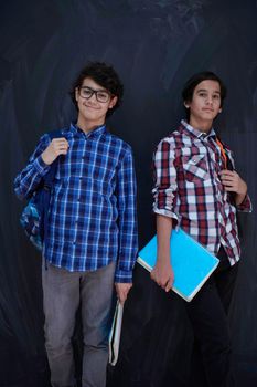 Arabic teenagers group  portrait against black chalkboard wearing backpack and books in school classroom