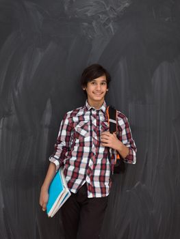 Arab teenager with backpack wearing casual school look against a black chalkboard background. High quality photo