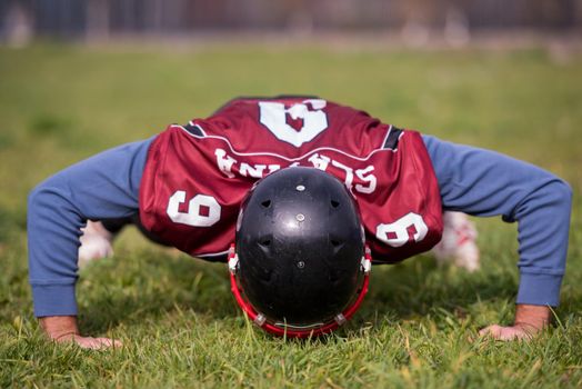 american football player doing push ups during training at the field