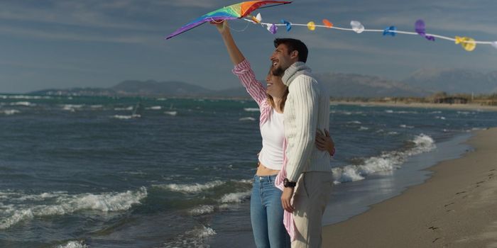 Loving Couple Flying A Kite at Beach and having fun on autumn day