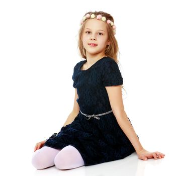 Beautiful little girl kneels in the studio on a white background. The concept of beauty and fashion, children's emotions. Isolated.