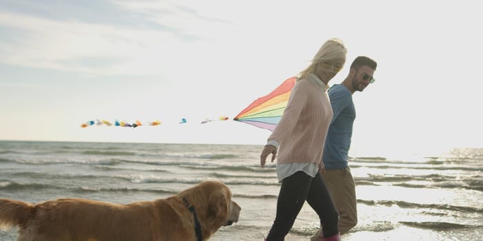 Couple Running On The Beach Holding Their Hands with dog On autmun day