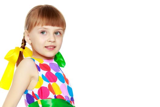 A sweet little blonde girl with long pigtails, in which large colored bows are braided, and a short bangs on her head. In a short summer dress, a pattern of multi-colored circles.