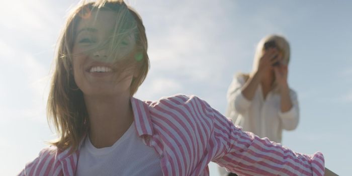 Two Girl Friends Taking Photo with Smartphone On Empty Beach during autumn day