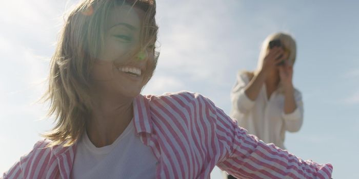 Two Girl Friends Taking Photo with Smartphone On Empty Beach during autumn day