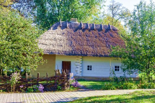 Old clay hut with a thatched roof in the village. Ukraine.