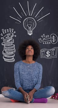 portrait of a beautiful friendly African American woman with a curly afro hairstyle and lovely smile sitting isolated on a gray background