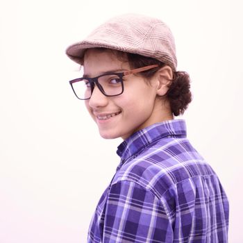 portrait  of smart looking arab teenager with glasses wearing a hat in casual school look isolated on white copy space