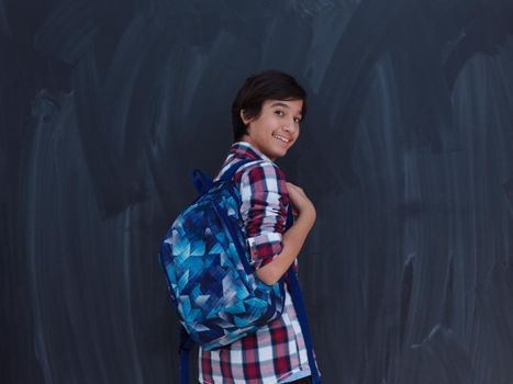 arab teenager with backpack wearing  casual school look against black chalkboard background