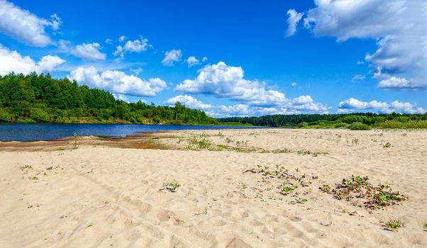 Wild sandy beach near the river on a fine summer day. Only blue sky, sand and a quiet river. Russia, Kostroma region, Kozionikha village. The concept of tourism, native land.