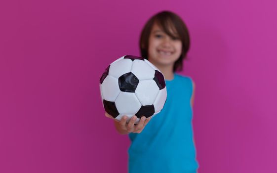 Portrait of young Arabic boy with soccer ball isolated against  pink background and copy space