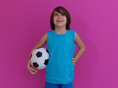 Portrait of young Arabic boy with soccer ball isolated against  pink background and copy space