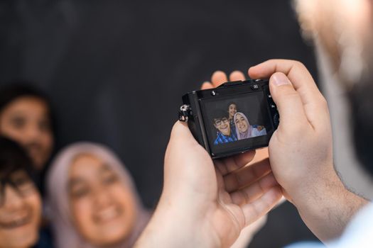 A father with a camera photographs his children as they pose with a smile on their face. High quality photo