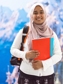 a portrait of a happy Middle Eastern university student in front of a snowy mountain in the background. High quality photo