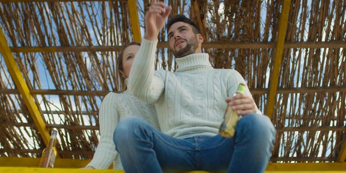 Couple Drinking Beer Together on beach during autumn time