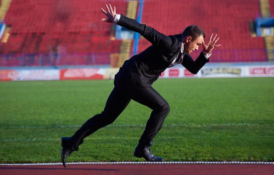 business man in start position ready to run and sprint on athletics racing track