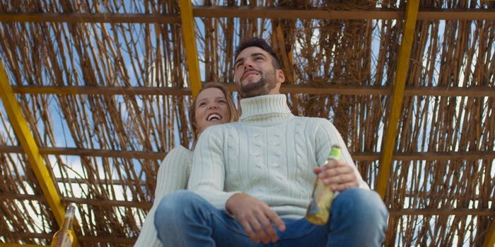 Couple Drinking Beer Together on beach during autumn time