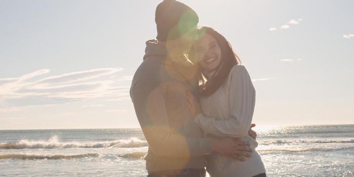 Cool Couple Laughing and hugging In Front Of Beach at beautiful autumn day