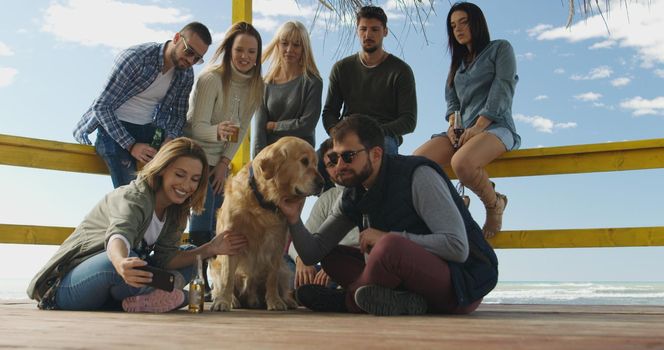 Happy Group Of Friends Hanging Out At Beach House having fun and drinking beer on autumn day