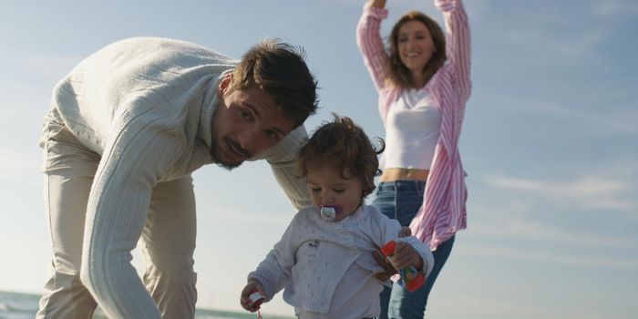 Family with kids resting and having fun at beach during autumn day