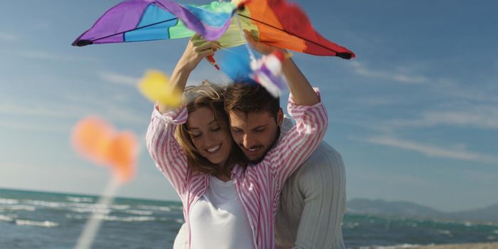 Loving Couple Flying A Kite at Beach and having fun on autumn day