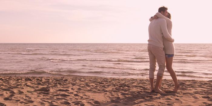 Young couple having fun on beach during autumn sunny day