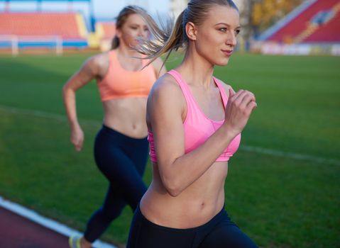 athlete woman group  running on athletics race track on soccer stadium and representing competition and leadership concept in sport