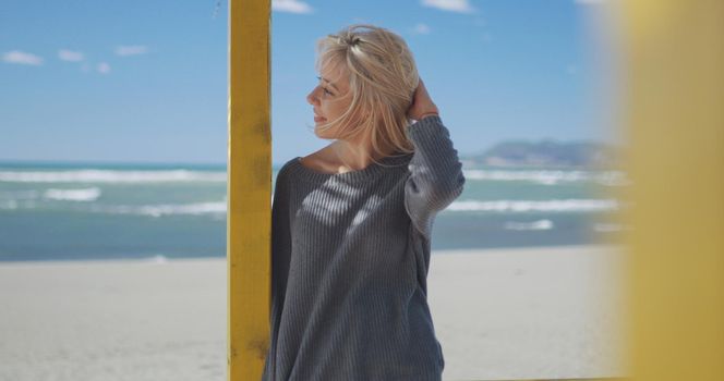 Young woman on the beach. The girl enjoying the warm autumn day. Portrait of beautiful girl near the water