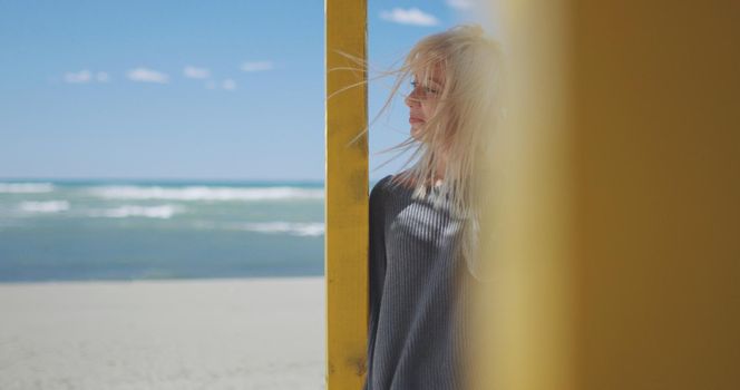 Young woman on the beach. The girl enjoying the warm autumn day. Portrait of beautiful girl near the water