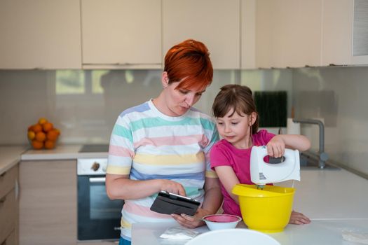 little girl and mom making tastz cake in kithen, family having fun at home 