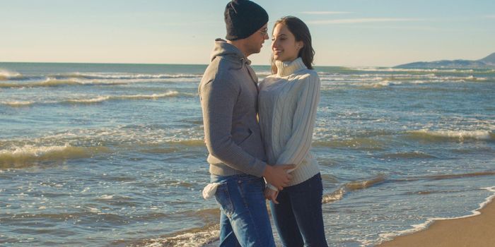 Cool Couple Laughing and hugging In Front Of Beach at beautiful autumn day