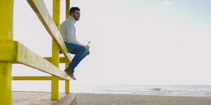 Man Drinking Beer on beach during autumn time