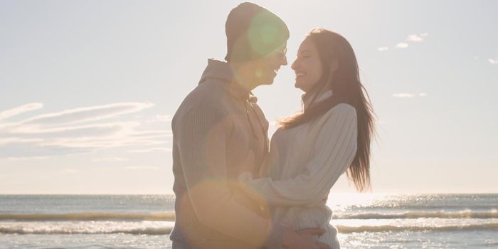 Cool Couple Laughing and hugging In Front Of Beach at beautiful autumn day