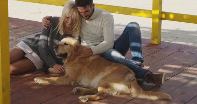 Couple With A Dog enjoying time  together On The Beach at autumn day