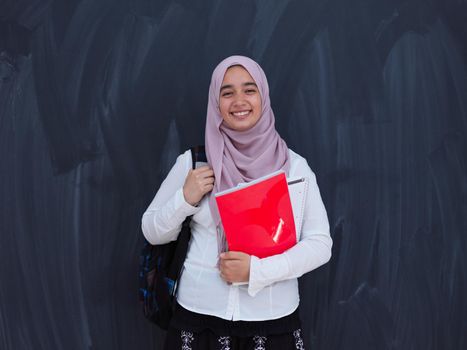 portrait of happy female middle eastern university student against black chalkboard in classroom