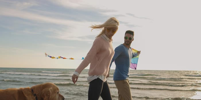 Couple Running On The Beach Holding Their Hands with dog On autmun day