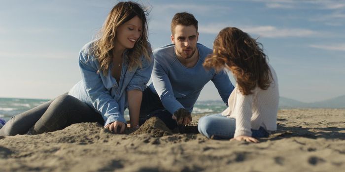 Family with kids resting and having fun at beach during autumn day