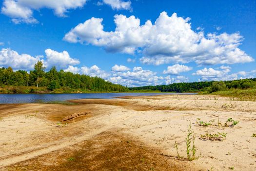 Wild sandy beach near the river on a fine summer day. Only blue sky, sand and a quiet river. Russia, Kostroma region, Kozionikha village. The concept of tourism, native land.