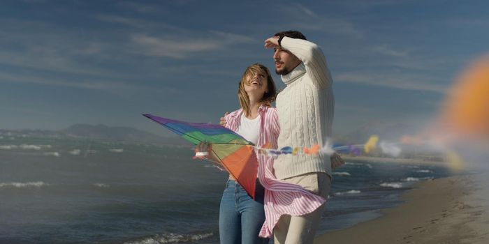 Loving Couple Flying A Kite at Beach and having fun on autumn day