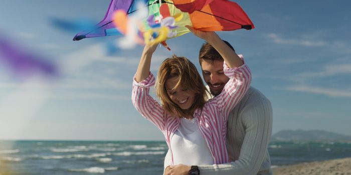 Loving Couple Flying A Kite at Beach and having fun on autumn day