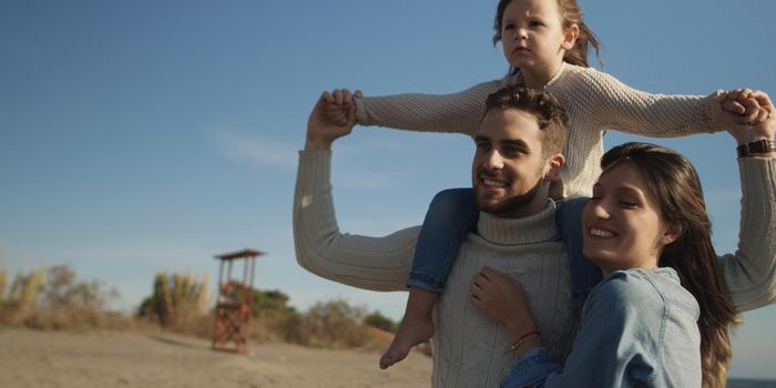 Family with kids resting and having fun at beach during autumn day