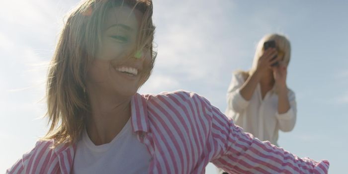 Two Girl Friends Taking Photo with Smartphone On Empty Beach during autumn day