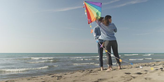 Young Couple having fun and Playing With A Kite On The Beach at autumn day