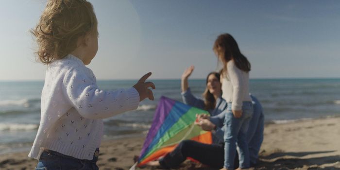 Family with kids resting and having fun at beach during autumn day