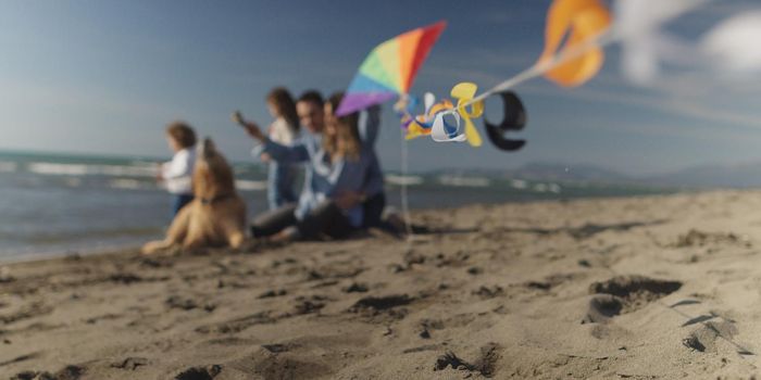 Family with kids resting and having fun at beach during autumn day