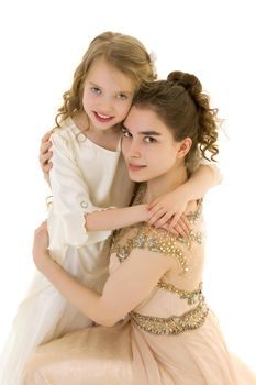 Beautiful young girl hugging her little sister. The concept of a happy childhood, family values. Isolated on white background.