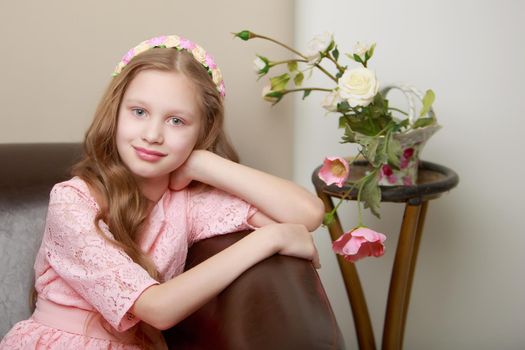 Happy little girl with a bouquet of flowers sitting on the couch. The concept of a holiday, a spring mood.