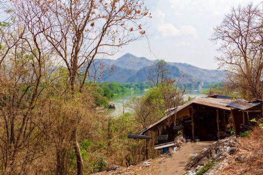 Wooden hut in the jungle of Thailand, among the trees on the banks of the river Kwai. The concept of tourism, family vacation.